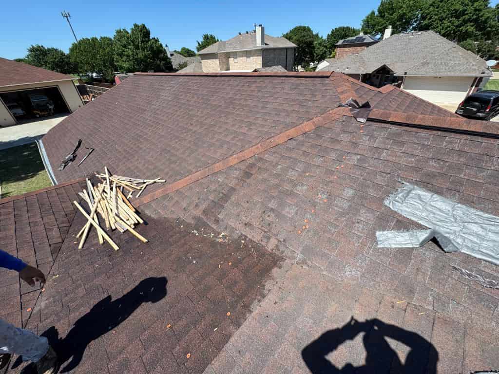 Weathered asphalt shingle roof with roofing tools during a damage assessment.