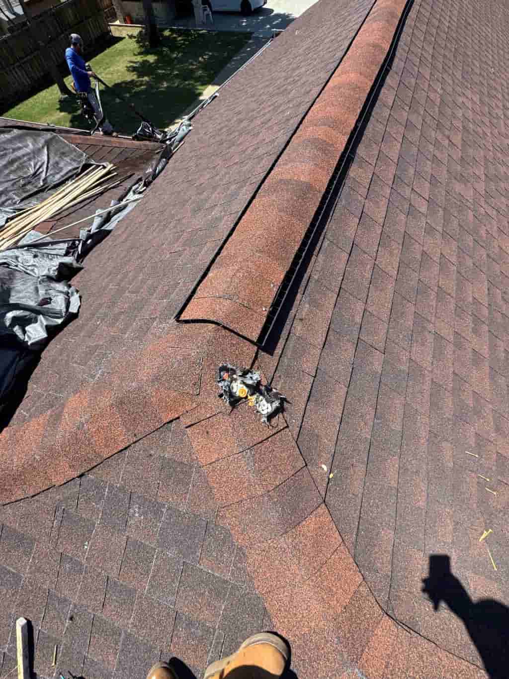 Exposed ridge section and asphalt shingles during residential roof repair work.